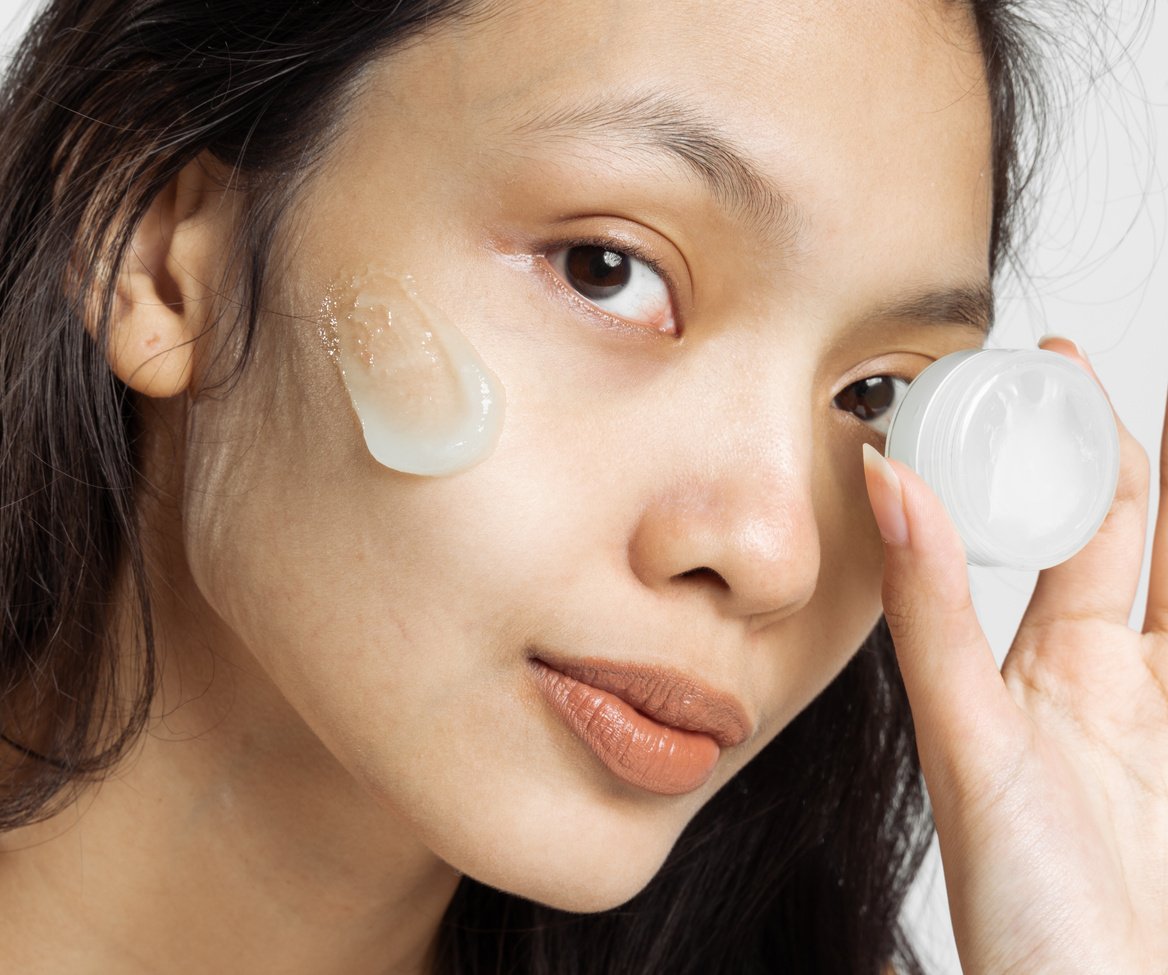 Closeup Portrait of Woman with Facial Moisturizer Holding Cosmetic Container